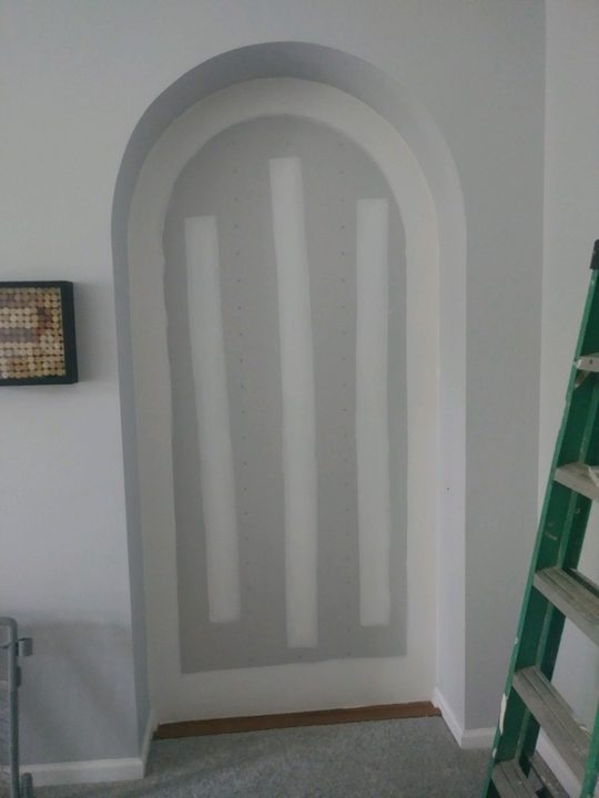After: Arched doorway boarded up, then plastered to a finished arch